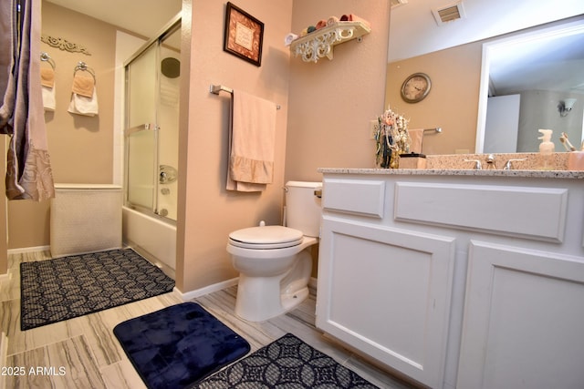 bathroom featuring visible vents, baseboards, toilet, and shower / bath combination with glass door