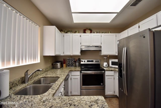 kitchen featuring appliances with stainless steel finishes, a sink, light stone counters, white cabinets, and under cabinet range hood