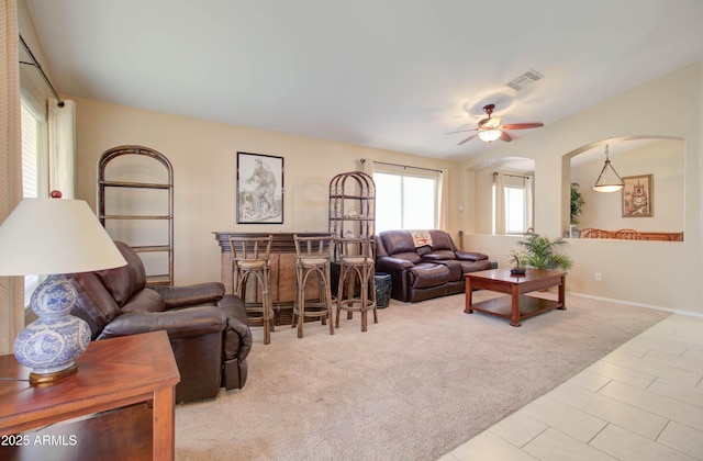 14298 W Amelia Ave, Goodyear, AZ 85395 - carpeted living area featuring a bar, ceiling fan, arched walkways, tile patterned floors, and baseboards