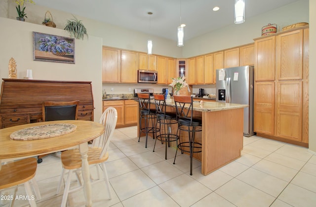 14298 W Amelia Ave, Goodyear, AZ 85395 - kitchen featuring appliances with stainless steel finishes, light tile patterned floors, a center island, a breakfast bar, and hanging light fixtures