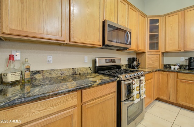14298 W Amelia Ave, Goodyear, AZ 85395 - kitchen with appliances with stainless steel finishes, light tile patterned floors, glass insert cabinets, and dark stone counters