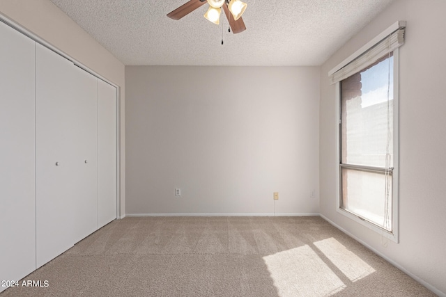 unfurnished bedroom with a closet, ceiling fan, a textured ceiling, and light colored carpet