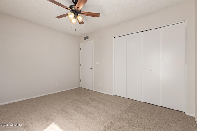 unfurnished bedroom featuring light carpet, a closet, a textured ceiling, and ceiling fan