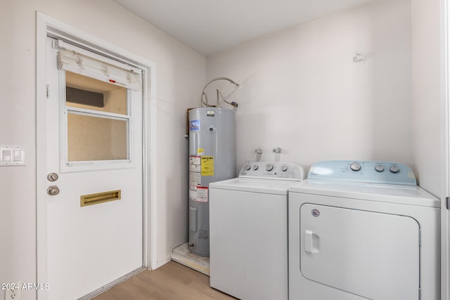 laundry room with water heater, washing machine and dryer, and light wood-type flooring