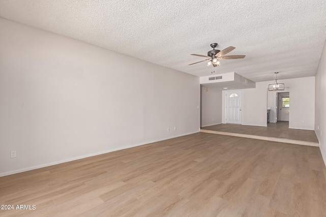 unfurnished living room featuring light hardwood / wood-style flooring, a textured ceiling, and ceiling fan with notable chandelier