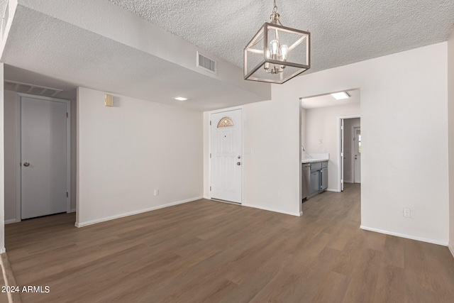 interior space with dark wood-type flooring, a textured ceiling, and an inviting chandelier