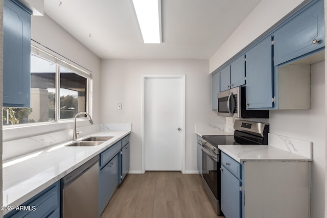 kitchen with stainless steel appliances, sink, light wood-type flooring, and blue cabinets