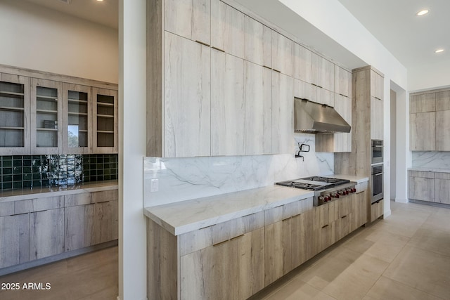 kitchen featuring stainless steel gas stovetop, light brown cabinetry, and decorative backsplash