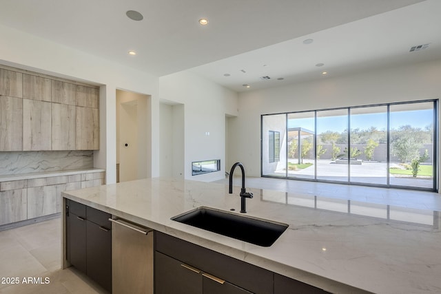 kitchen featuring sink, dark brown cabinets, light stone counters, tasteful backsplash, and stainless steel dishwasher