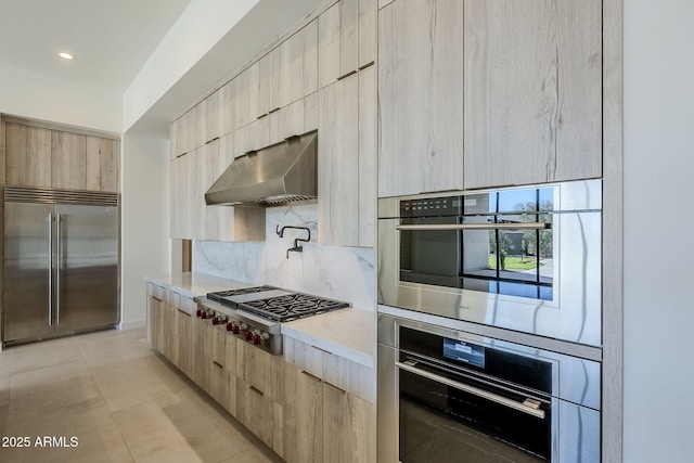 kitchen featuring stainless steel appliances, light brown cabinetry, decorative backsplash, and light tile patterned floors