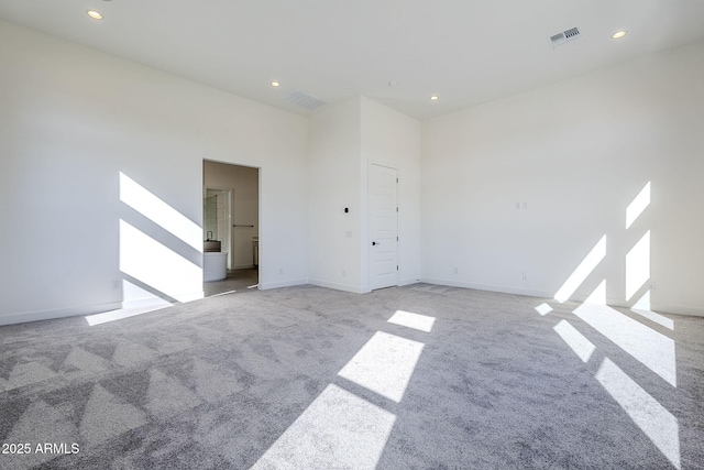 carpeted spare room featuring a towering ceiling