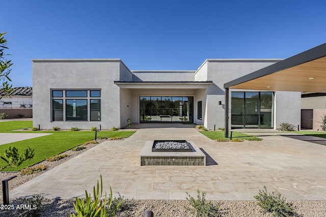 rear view of property featuring a yard, a patio area, and an outdoor fire pit