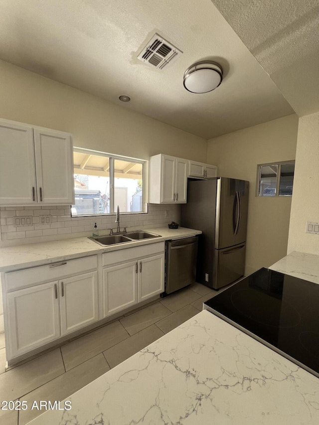 kitchen featuring light tile patterned floors, appliances with stainless steel finishes, sink, and white cabinets