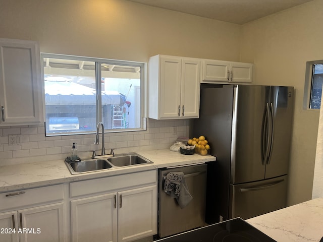 kitchen with sink, white cabinets, backsplash, light stone counters, and stainless steel appliances