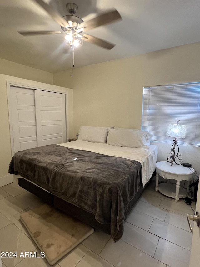 bedroom with light tile patterned flooring, ceiling fan, and a closet