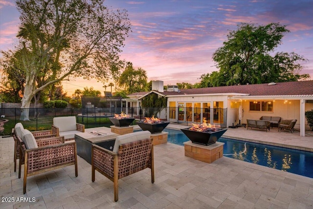 1831 E Rovey Ave, Phoenix, AZ 85016 - pool at dusk with an outdoor living space with a fire pit, a patio, and fence