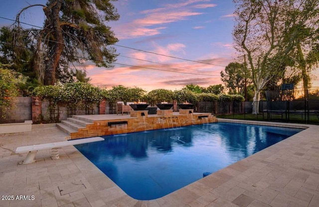 1831 E Rovey Ave, Phoenix, AZ 85016 - pool at dusk featuring a patio, a fenced backyard, a diving board, and a trampoline
