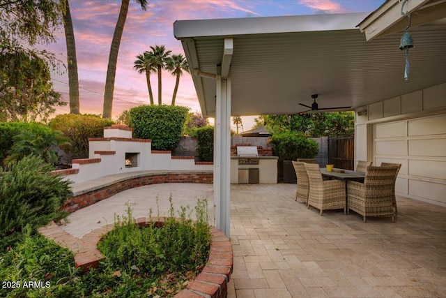1831 E Rovey Ave, Phoenix, AZ 85016 - patio terrace at dusk featuring area for grilling, a lit fireplace, fence, and outdoor dining space