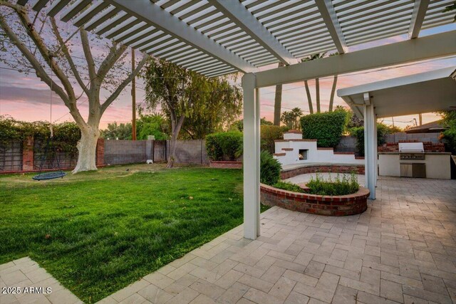1831 E Rovey Ave, Phoenix, AZ 85016 - yard at dusk featuring exterior fireplace, an outdoor kitchen, a patio area, and a pergola
