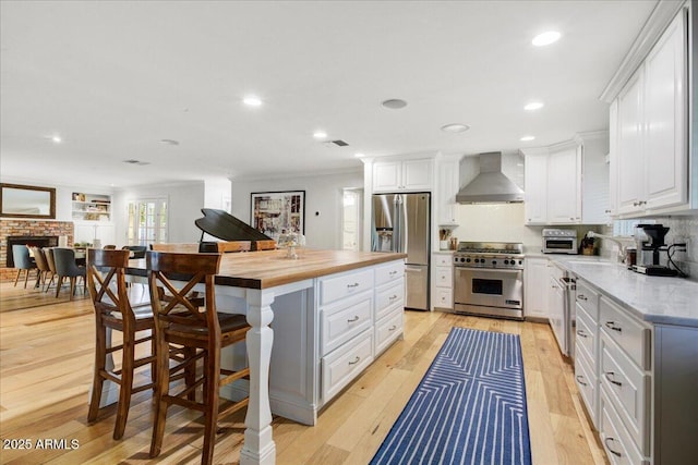 1831 E Rovey Ave, Phoenix, AZ 85016 - kitchen with appliances with stainless steel finishes, wall chimney range hood, butcher block counters, white cabinets, and recessed lighting