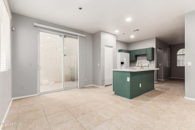 kitchen with white fridge with ice dispenser, a center island with sink, sink, and light tile patterned floors