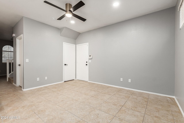 empty room featuring vaulted ceiling, light tile patterned floors, and ceiling fan