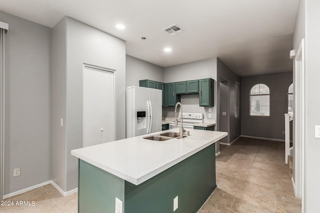 kitchen featuring green cabinetry, a kitchen island with sink, white appliances, sink, and light tile patterned flooring