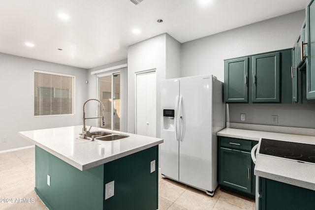 kitchen with sink, a center island with sink, green cabinets, white refrigerator with ice dispenser, and light stone countertops