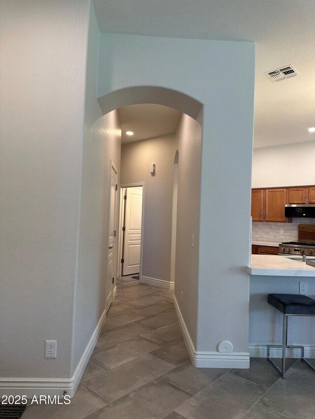 2013 E Valencia Dr, Phoenix, AZ 85042 - corridor featuring arched walkways, baseboards, recessed lighting, and tile patterned flooring