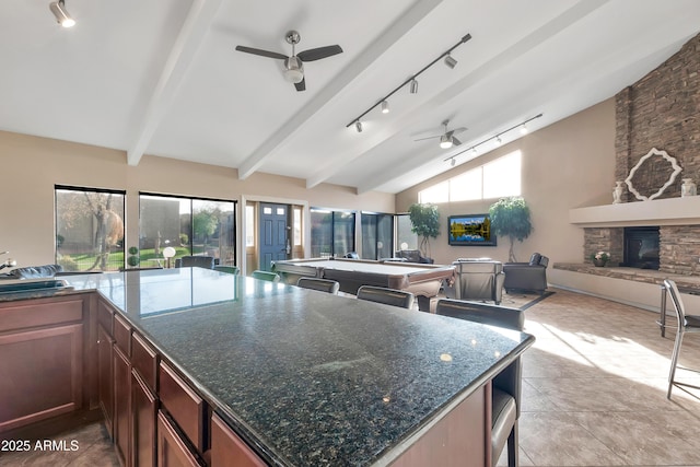 3825 E Camelback Rd Unit 182, Phoenix, AZ 85018 - kitchen featuring a ceiling fan, open floor plan, a fireplace, track lighting, and beamed ceiling