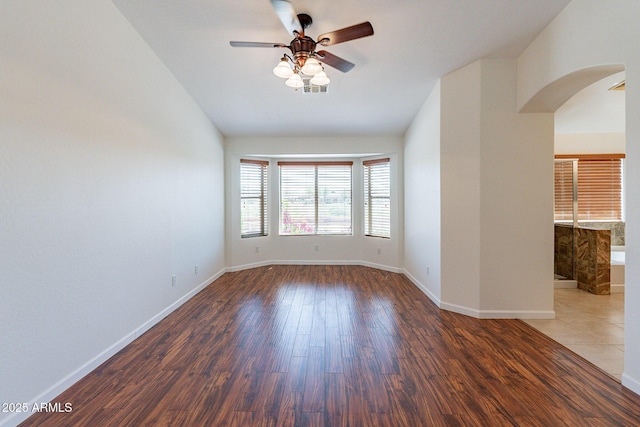 unfurnished room featuring dark hardwood / wood-style flooring, lofted ceiling, and ceiling fan