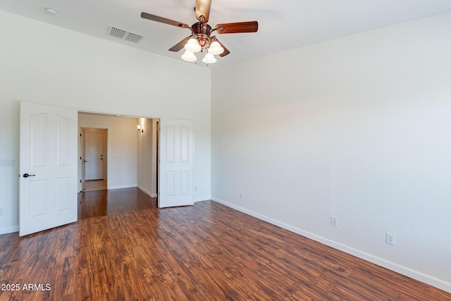 unfurnished room with ceiling fan, dark hardwood / wood-style flooring, and a high ceiling