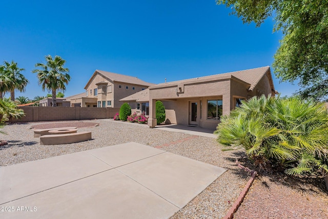 rear view of property featuring a patio area and a fire pit