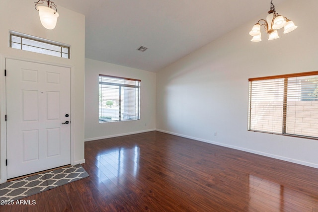 entryway with dark wood-type flooring, high vaulted ceiling, and a chandelier