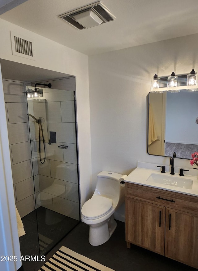 bathroom with vanity, toilet, and a tile shower