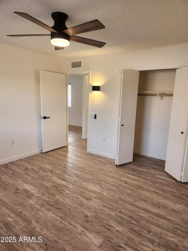 unfurnished bedroom with hardwood / wood-style flooring, ceiling fan, a textured ceiling, and a closet