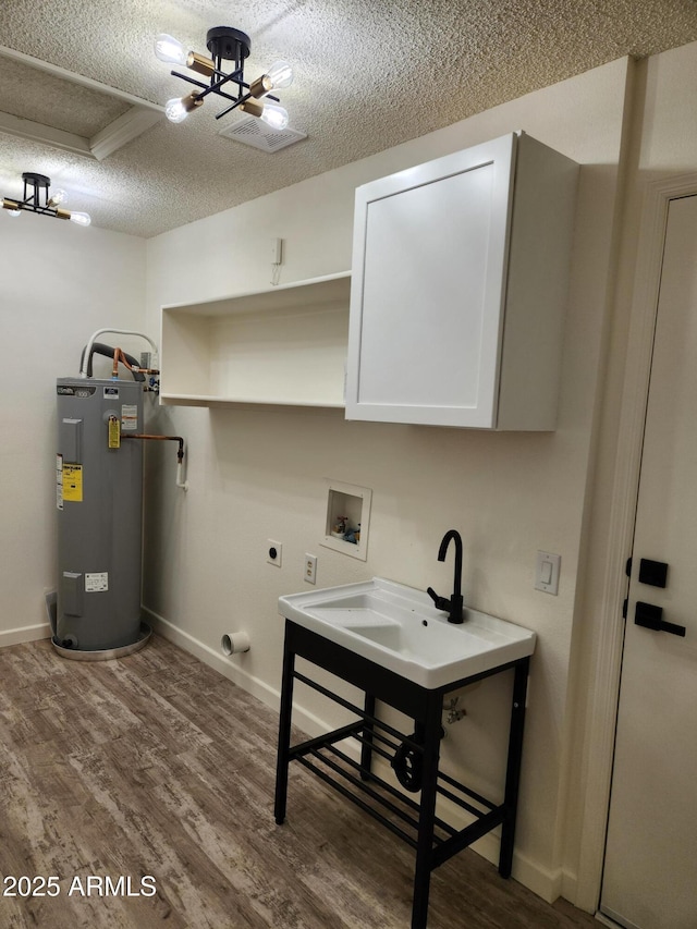 laundry area featuring cabinets, washer hookup, a textured ceiling, water heater, and hookup for an electric dryer