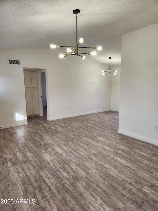 unfurnished room with a chandelier, a textured ceiling, and hardwood / wood-style flooring