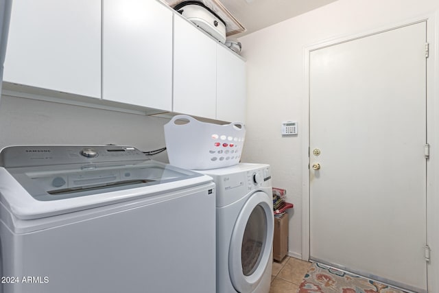 laundry area with washing machine and dryer, light tile patterned floors, and cabinets