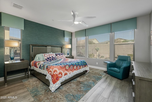 bedroom with multiple windows, wood-type flooring, and ceiling fan