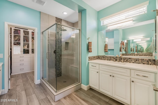 bathroom with walk in shower, vanity, and decorative backsplash