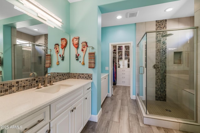 bathroom featuring tasteful backsplash, vanity, and walk in shower