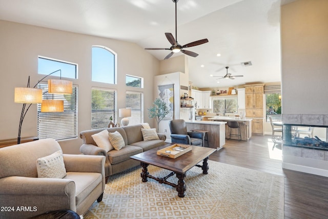 living room featuring ceiling fan, light hardwood / wood-style flooring, high vaulted ceiling, and a healthy amount of sunlight