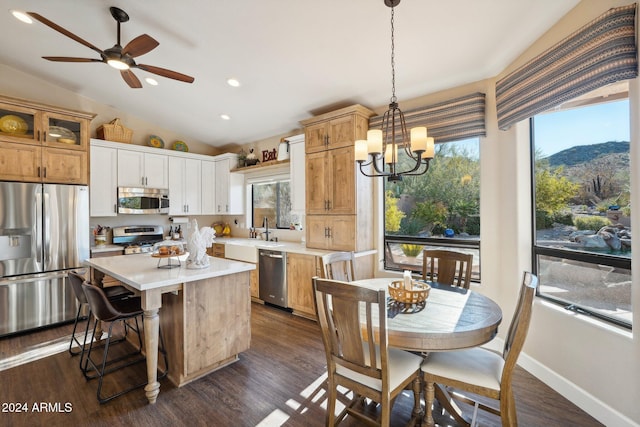 kitchen featuring stainless steel appliances, vaulted ceiling, a mountain view, a center island, and hanging light fixtures