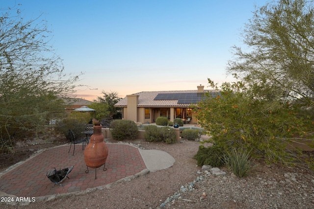 pueblo-style house featuring solar panels and a patio