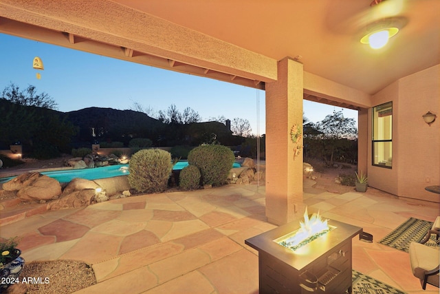 patio terrace at dusk featuring a mountain view and a fire pit