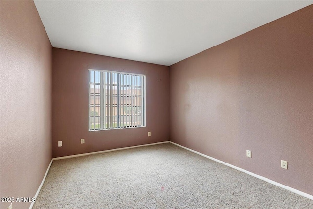 carpeted spare room featuring baseboards