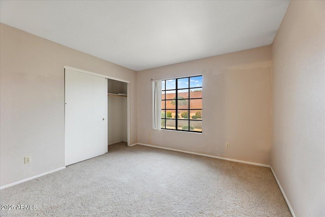unfurnished bedroom with a closet, carpet flooring, and baseboards