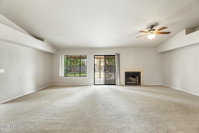 unfurnished living room featuring baseboards, vaulted ceiling, a tiled fireplace, a ceiling fan, and carpet
