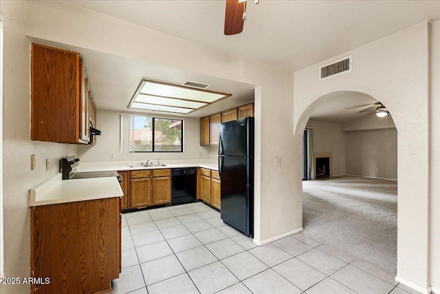 kitchen featuring a ceiling fan, visible vents, brown cabinetry, arched walkways, and black appliances